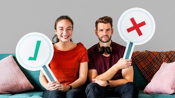 Frau und Mann sitzen nebeneinander während Frau ein Schild mit einem Hakerl und Mann ein Schild mit einem Kreuzerl in der Hand hält © rawpixel.com  - freepik.com 