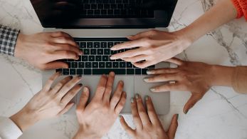 Sechs Hände auf Laptop © Mikhail Nilov  - pexels 