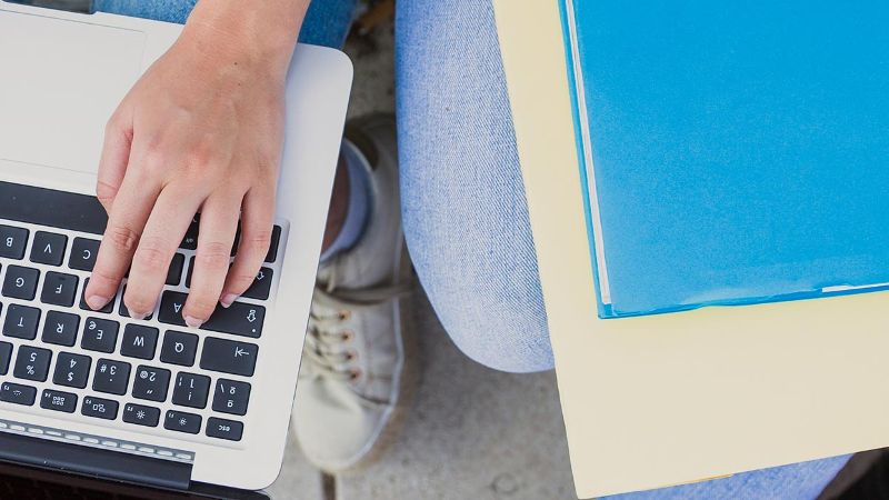 Hände auf einem Laptop und Bücher daneben ©  freepik.com 