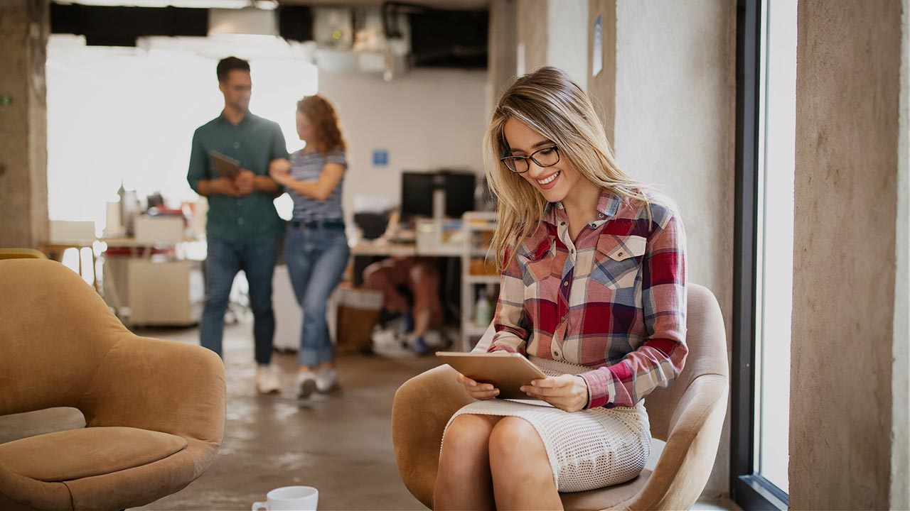Junge Frau schaut lächelnd auf ein Tablet ©  Unsplash+ 