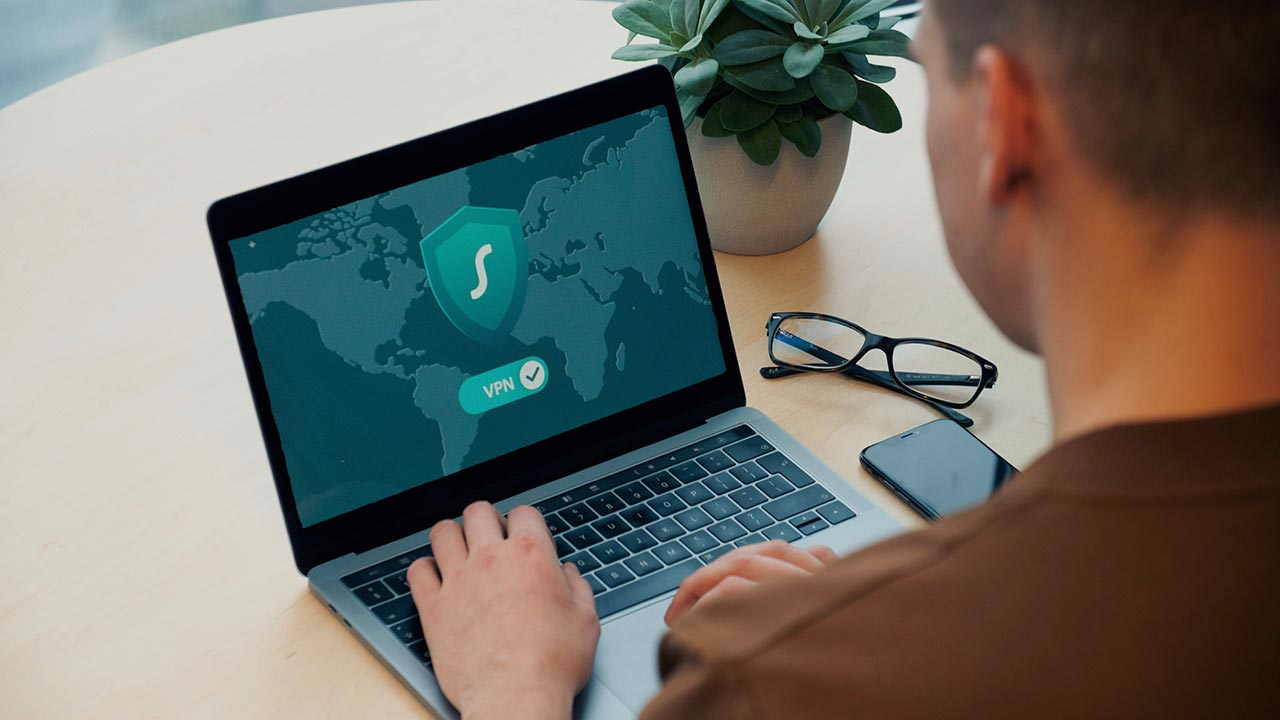 Mann sitzt vor Laptop auf dem ein Bild mit der Aufschrift VPN zu sehen ist © Dan Nelson - Unsplash