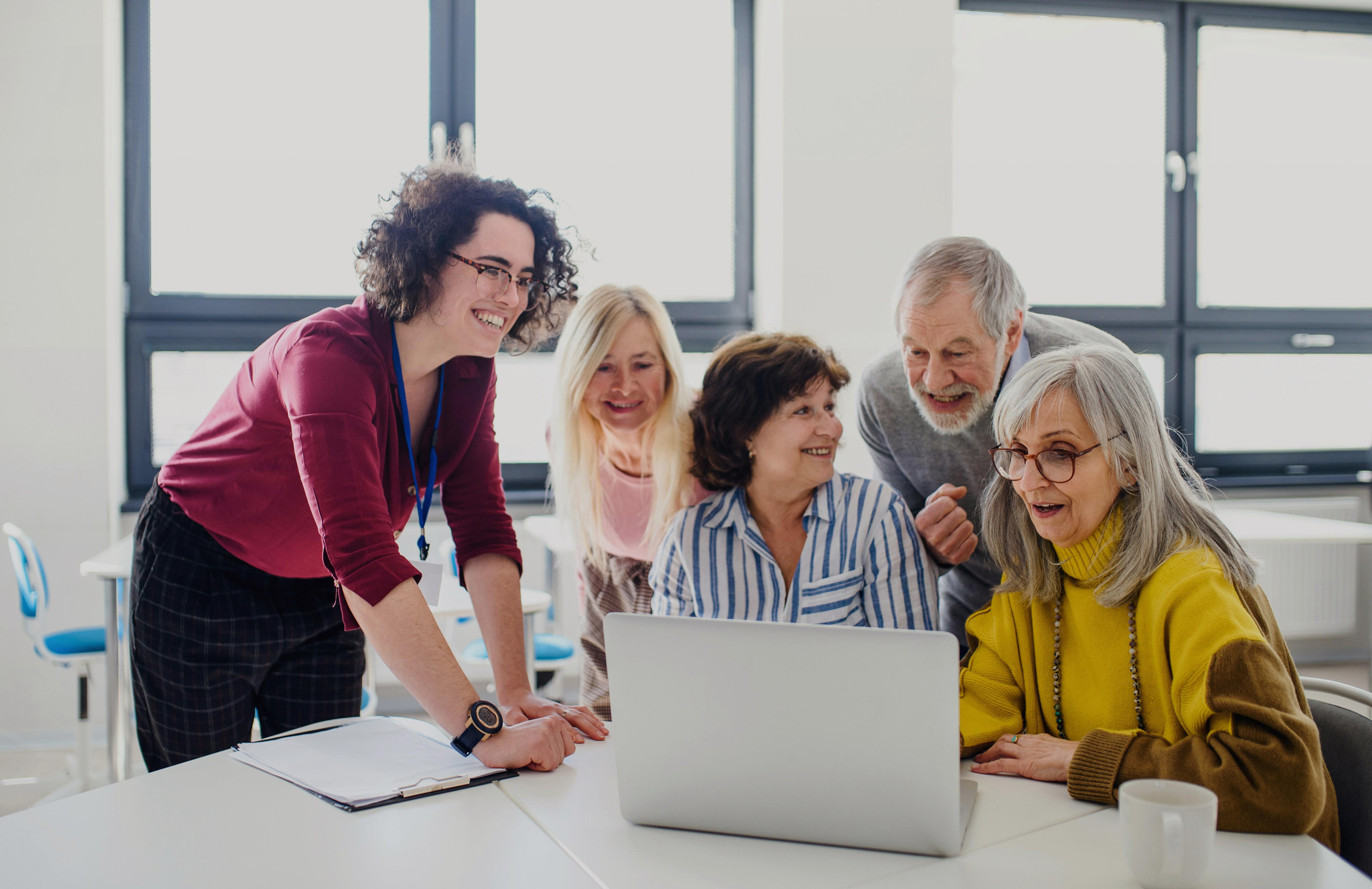 Gruppe von Personen sieht lächelnd auf einen Laptop © Unsplash+
