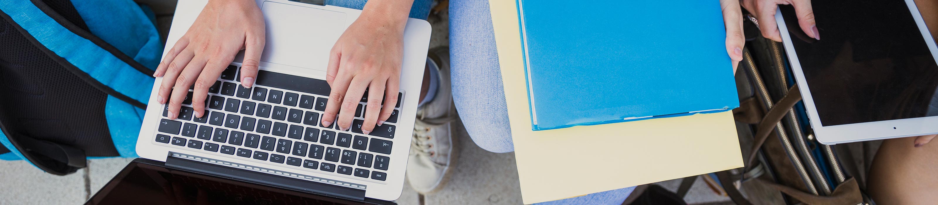 Hände auf einem Laptop und Bücher daneben © freepik.com