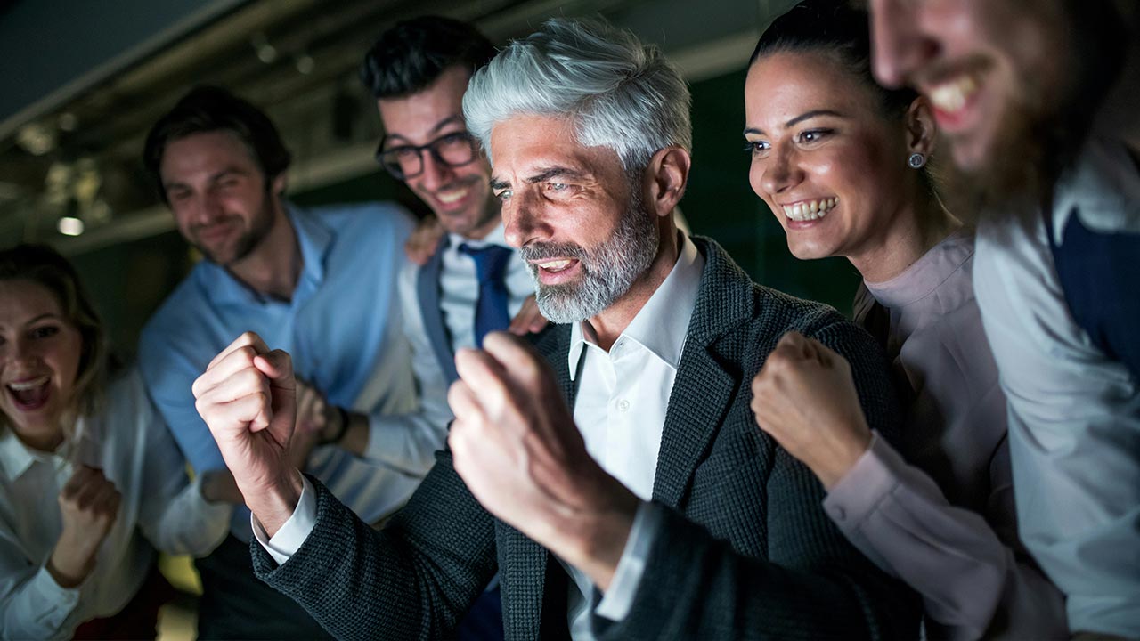 Gruppe von Personen jubelt vor einem Laptop © Unsplash+